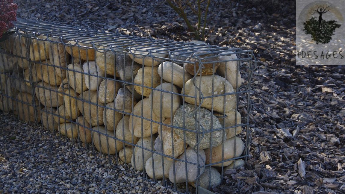 Le mélange pierres-métal, avec un gabion, rempli ici de galets de rivière, arrêtant la cascade de copeaux de b