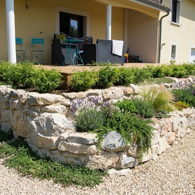 La terrasse bois soutenue par un mur en pierre aux dimensions potagère